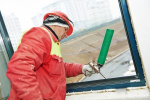 construction builder works with polyurethane foam during frame insulation at window installation